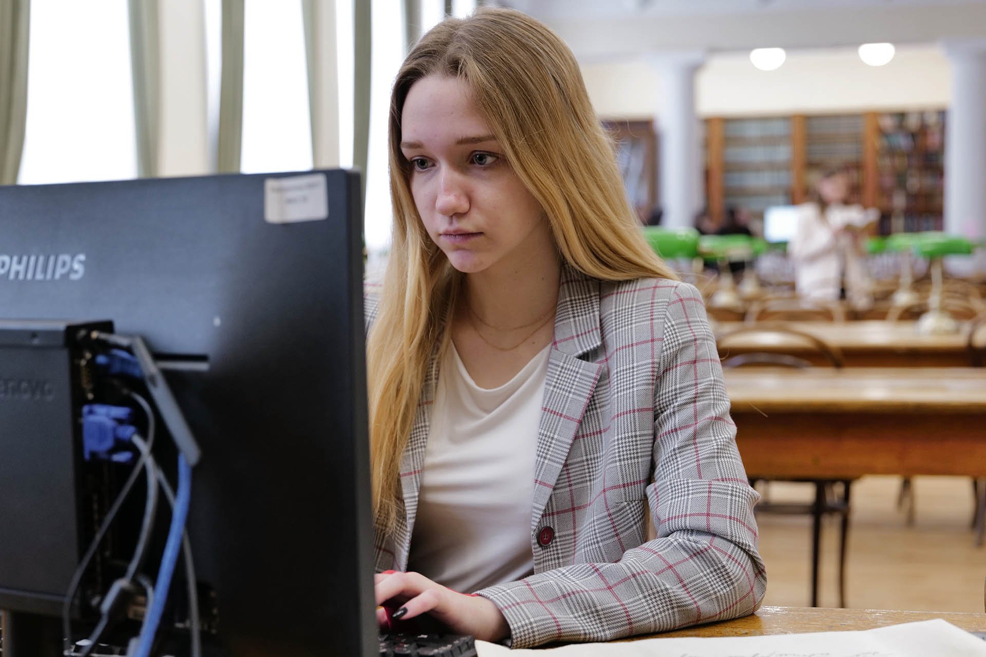 Студентка в университетской библиотеке за компьютером
