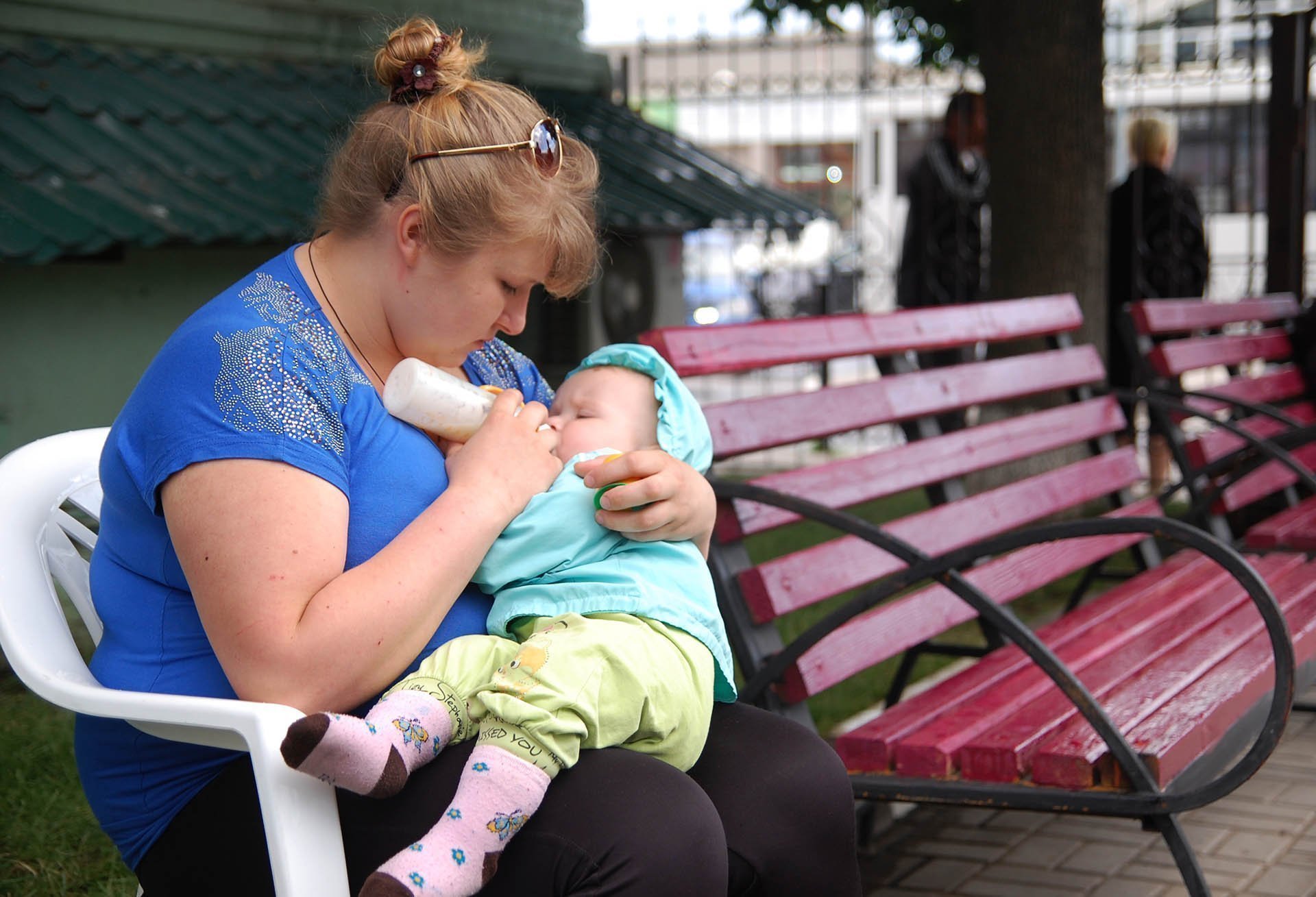 Женщина кормит ребенка молочной смесью из бутылочки