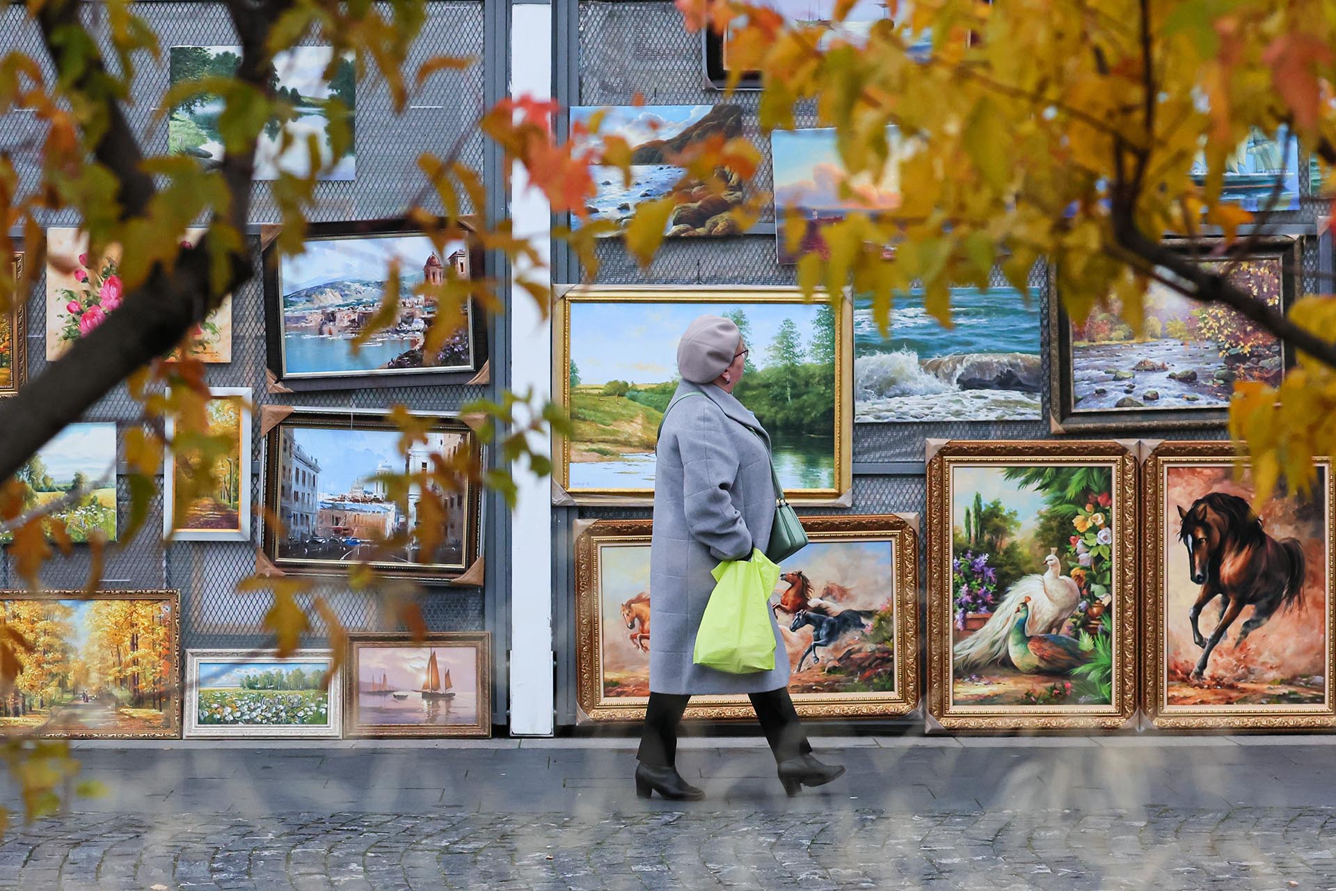 Женщина проходит мимо павильона с картинами