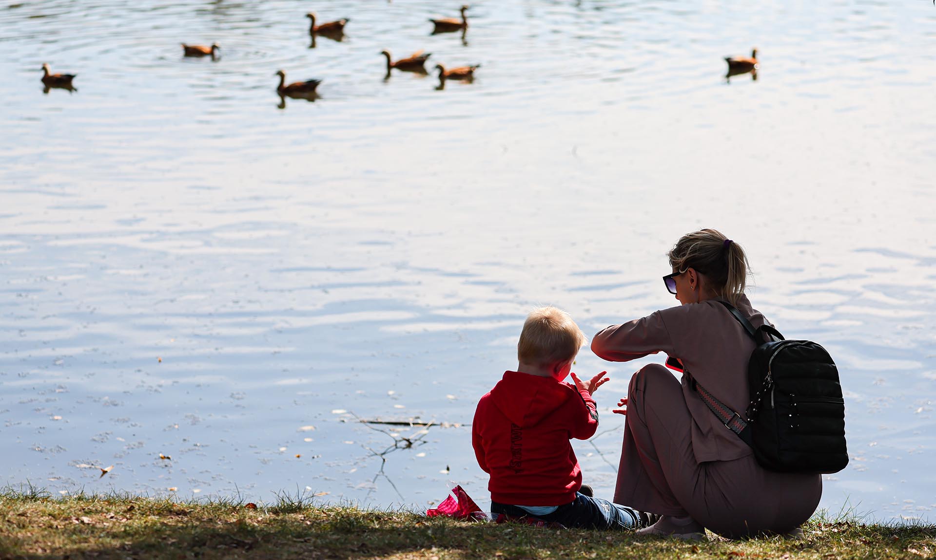 Женщина с ребенком на берегу пруда