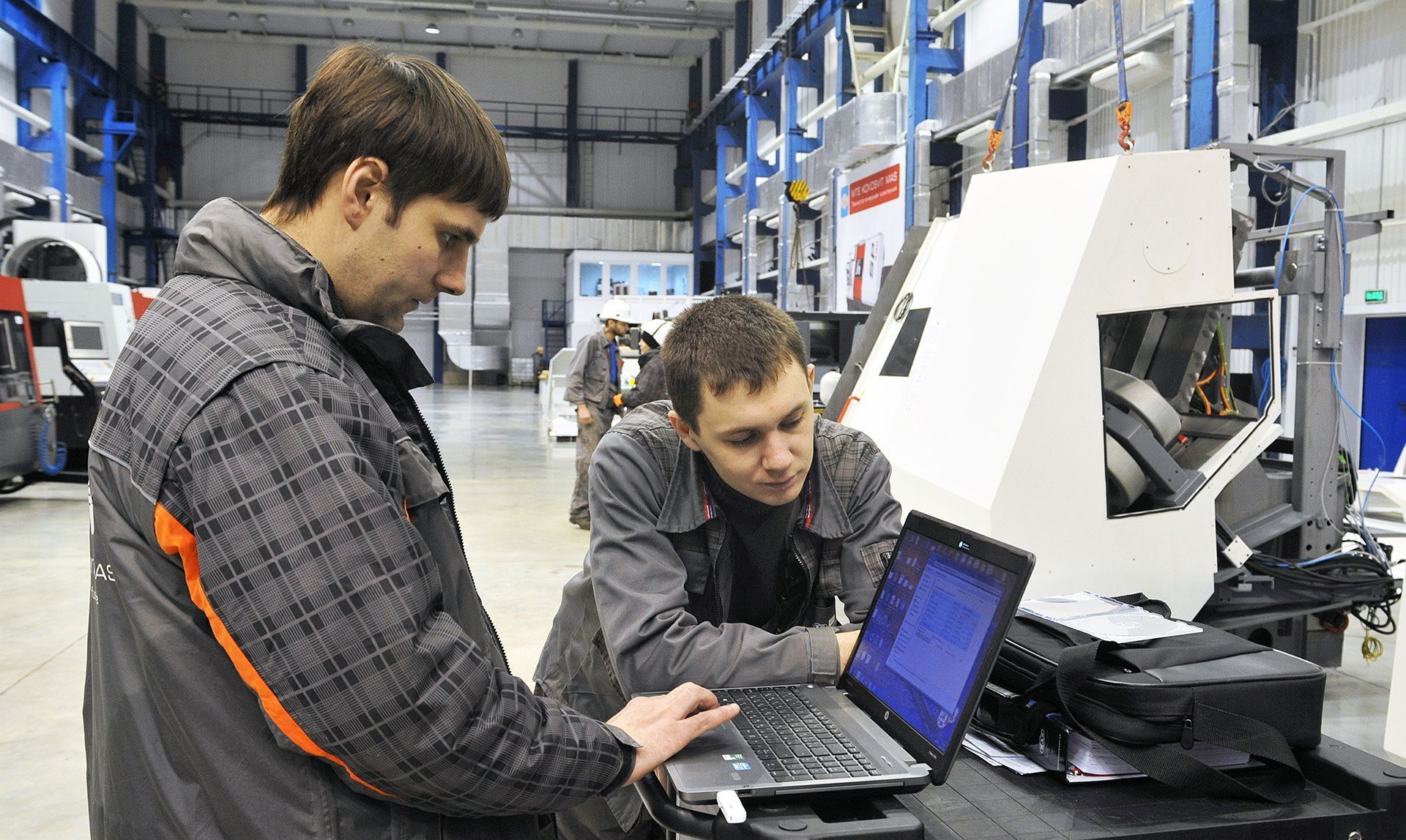 Сотрудники с ноутбуком на заводе