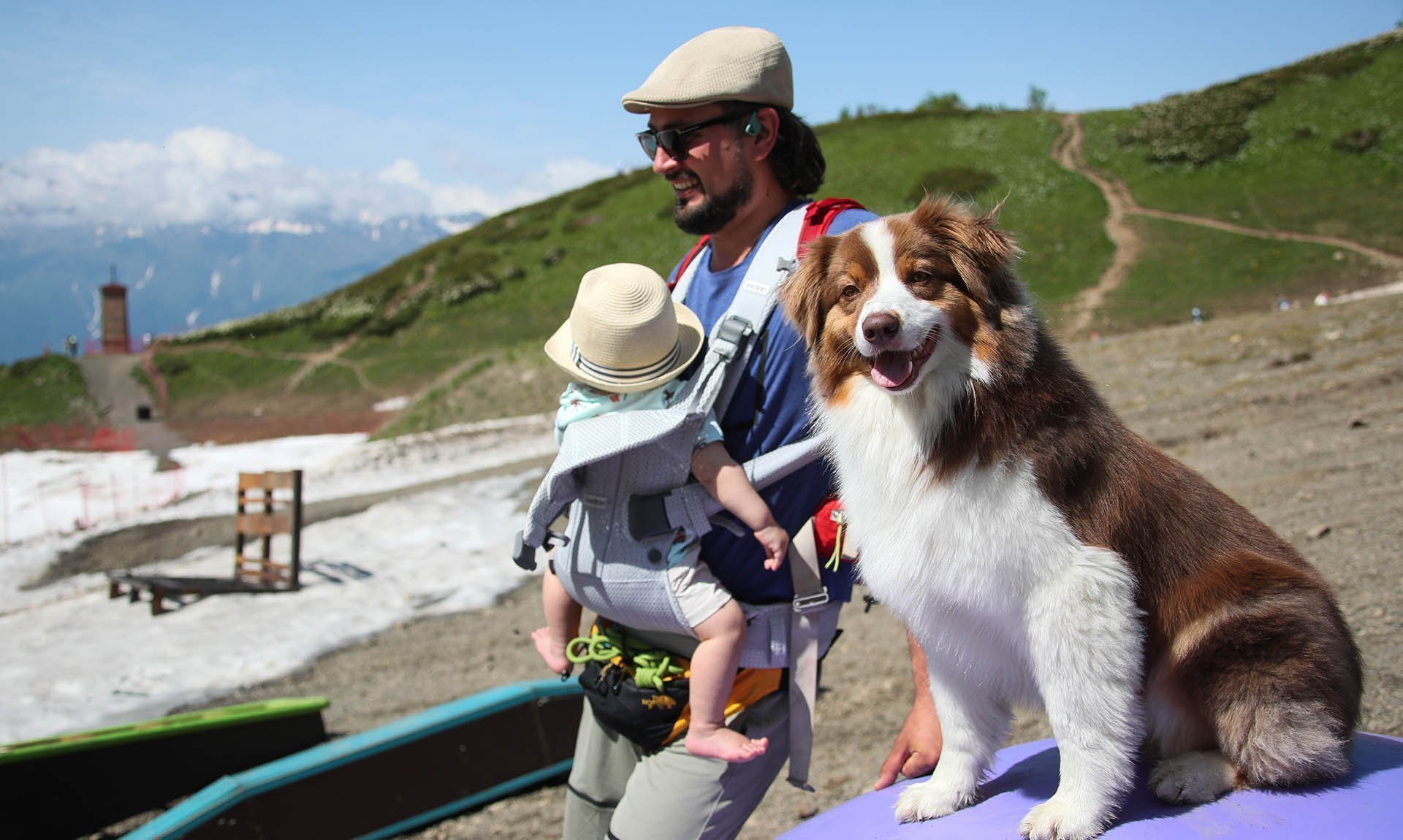 Мужчина с ребенком и собакой на территории горного курорта Красная поляна