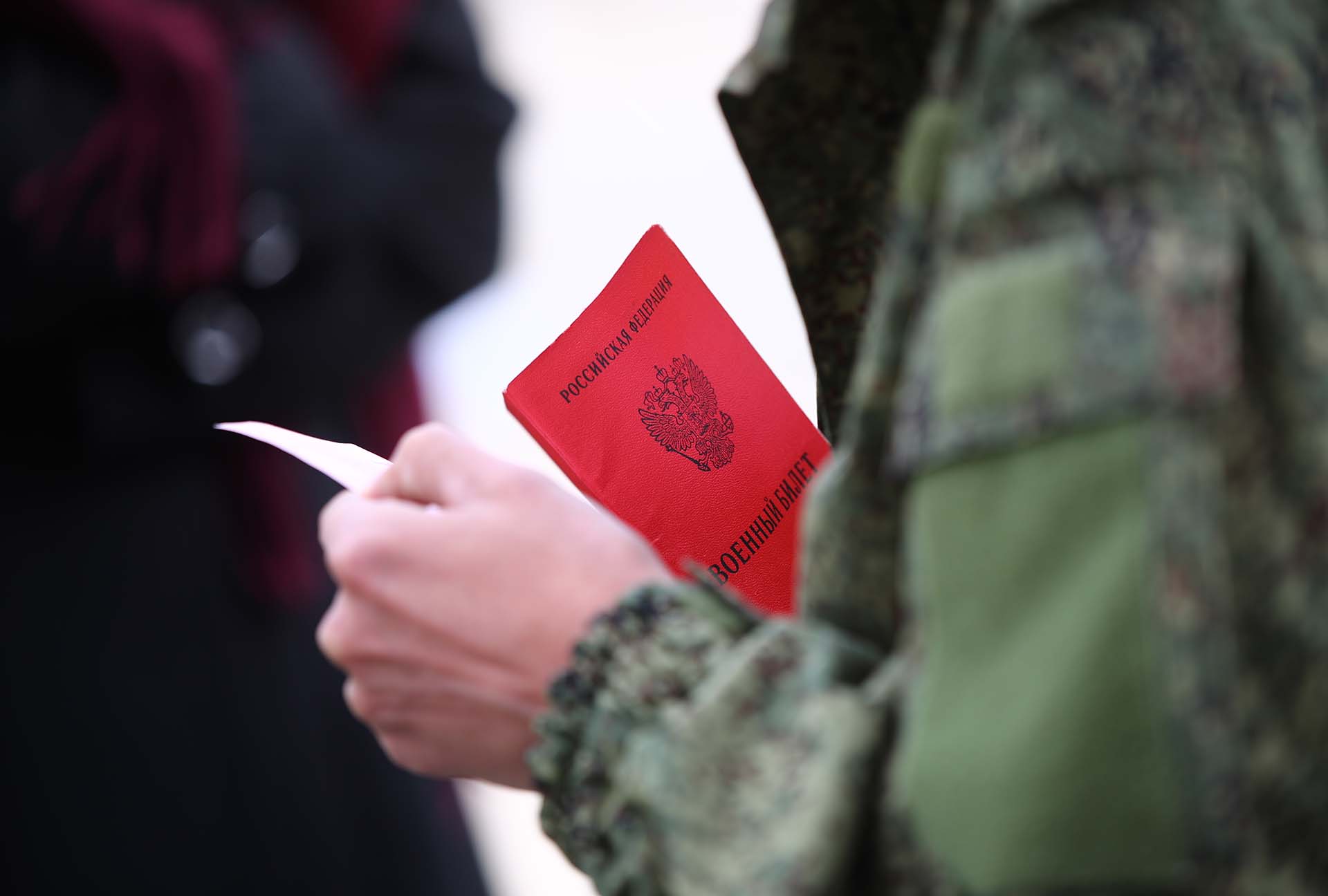 Военный билет в руках мужчины, призванного на воинскую службу