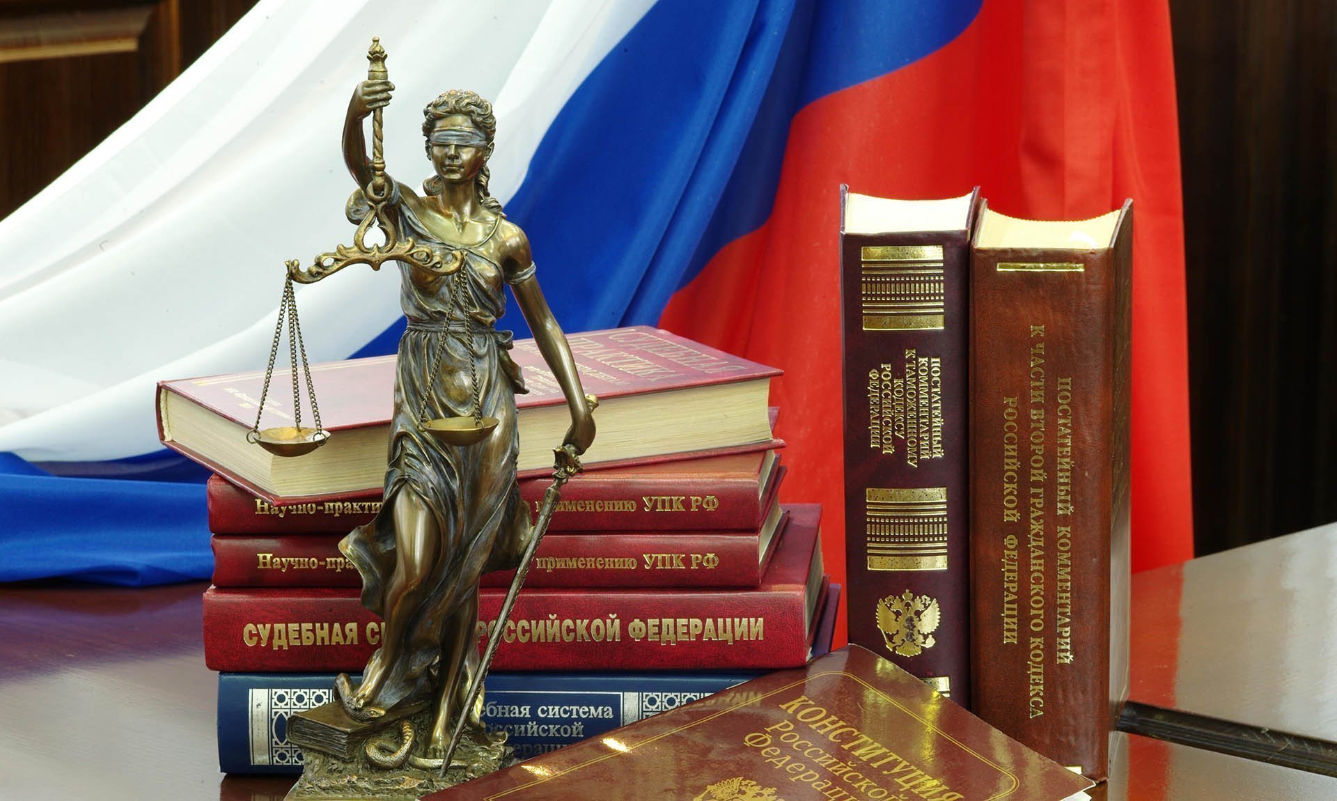 Статуя Фемиды и юридическая литература на столе в зале судебных заседаний