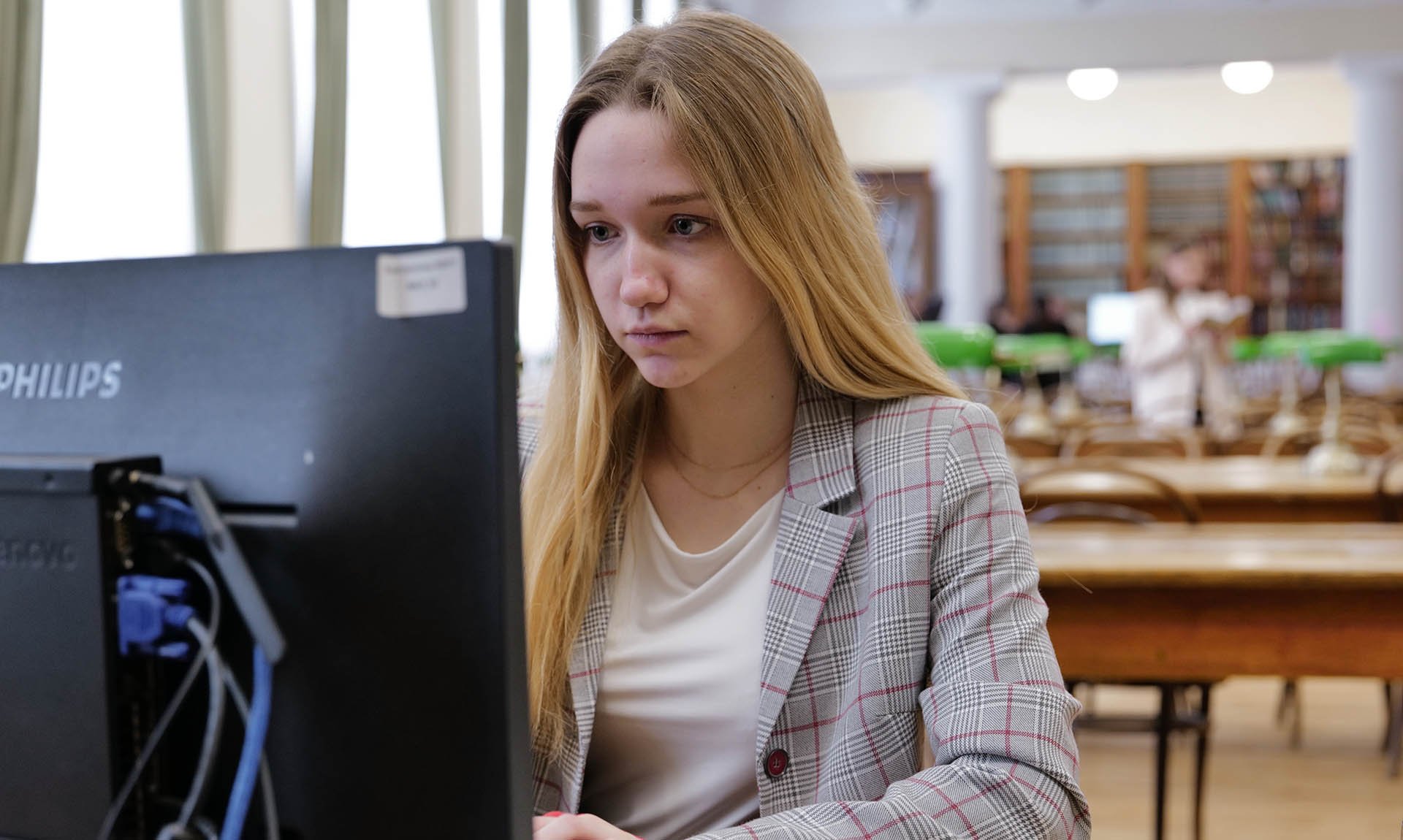 Студентка за компьютером в читальном зале