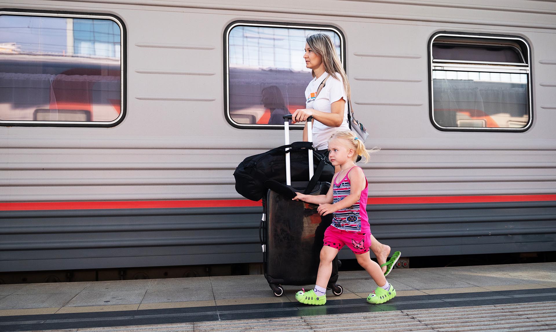 Женщина с ребенком и чемоданом около поезда