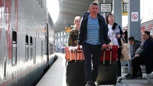 Пассажиры около двухэтажного поезда с чемоданами 