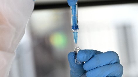 Медицинский работник набирает в шприц препарат в мобильном пункте вакцинации 