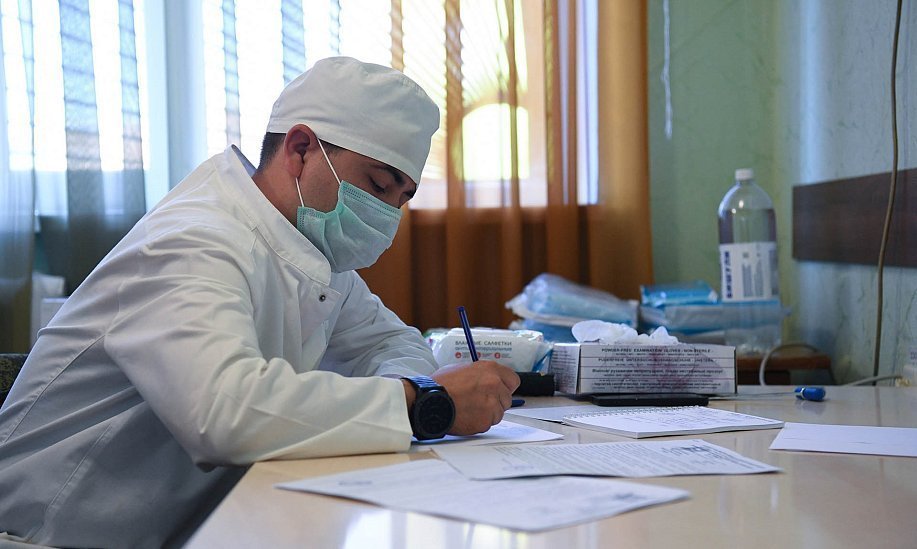 Медицинский работник заполняет  мед карту в кабинете