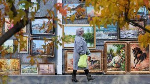 Женщина проходит мимо павильона с картинами