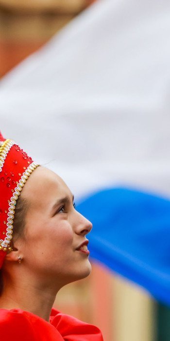 Девушки в национальных костюмах на фоне российского флага