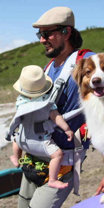 Мужчина с ребенком и собакой на территории горного курорта Красная поляна