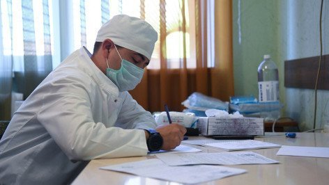 Медицинский работник заполняет  мед карту в кабинете