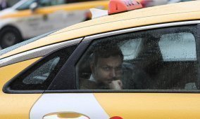 На заднем сиденье такси мужчина смотрит в окно в дождливую погоду