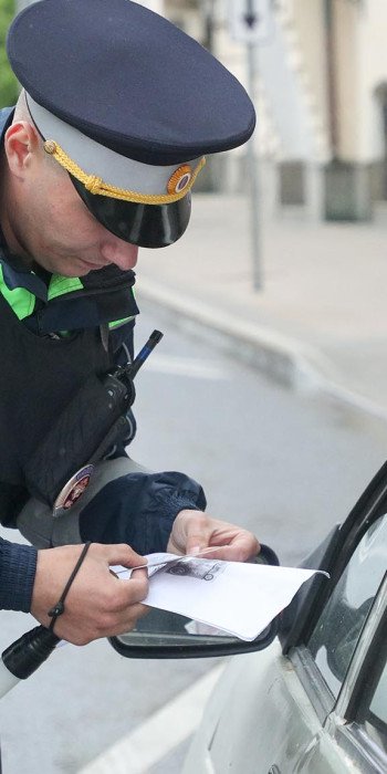 Сотрудник ГИБДД проверяет документы у водителя